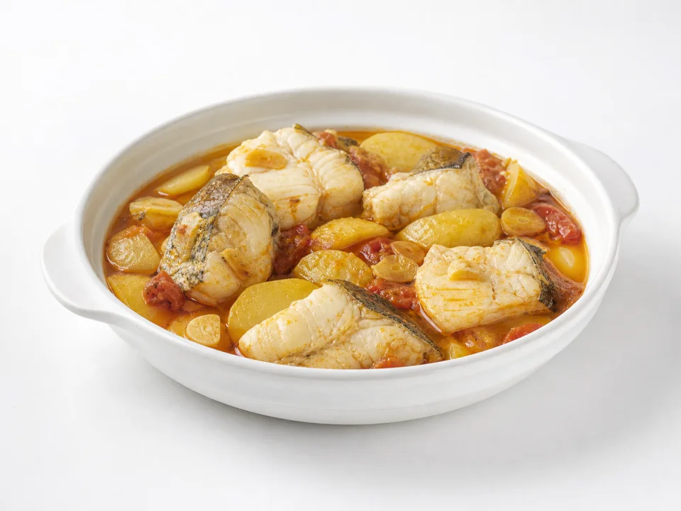 Cruet de peix met witte vis, aardappel en tomaat op een witte achtergrond