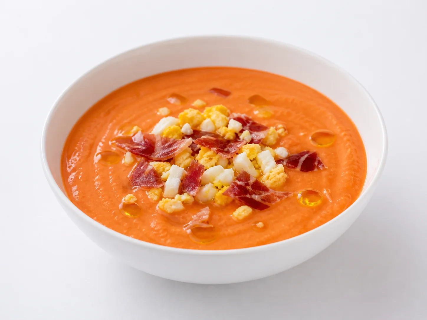 Salmorejo cordobés met ei en ham op een witte achtergrond