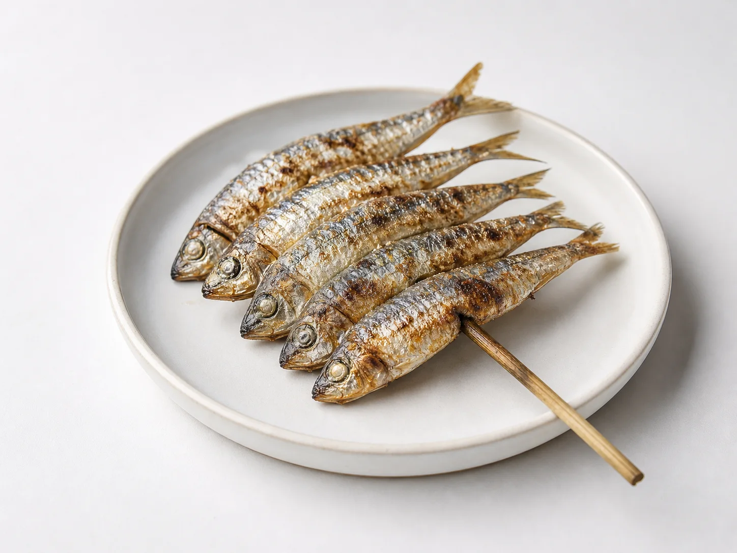 Espetos van geroosterde sardines uit Málaga op een witte achtergrond