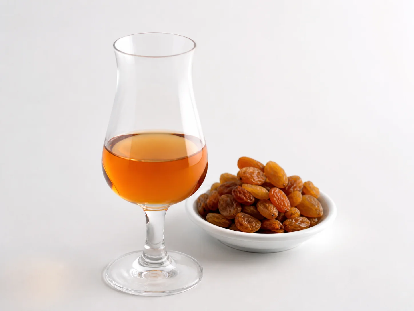 Glas zoete Málaga-wijn met muskaatrozijnen op een witte achtergrond